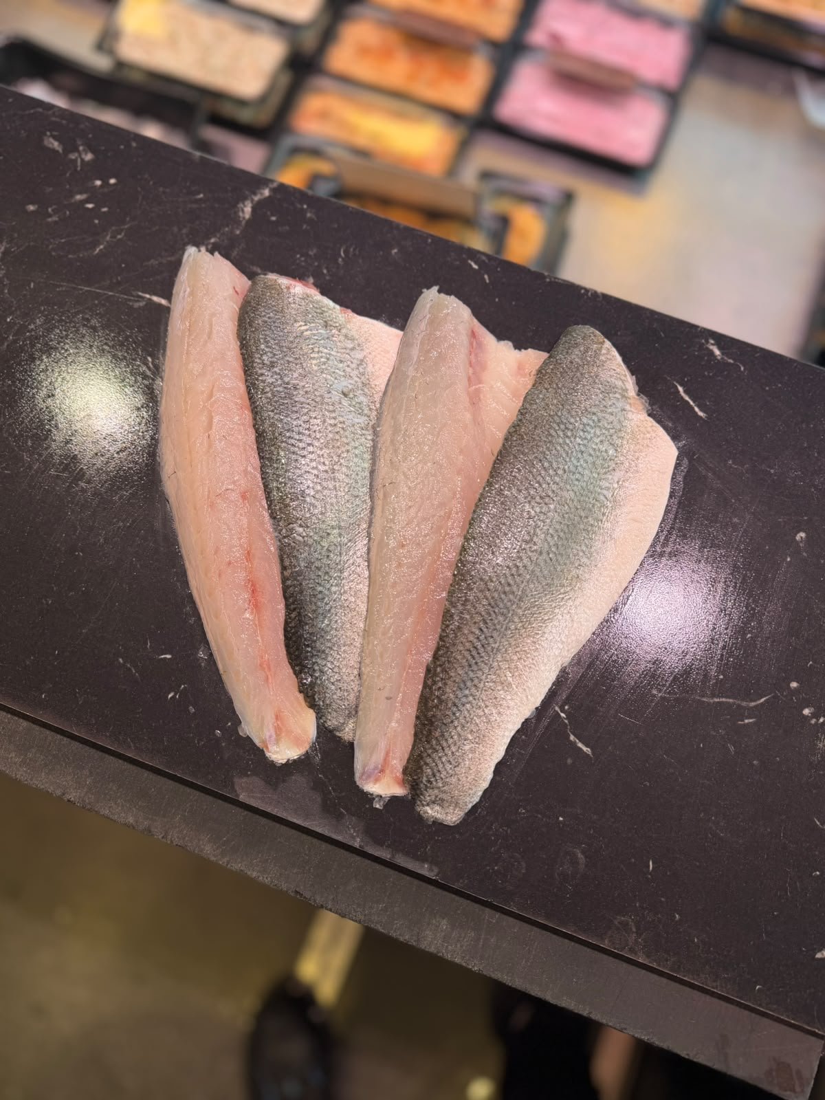 Verse zeebaarsfilets met huid, klaargelegd op de visbank